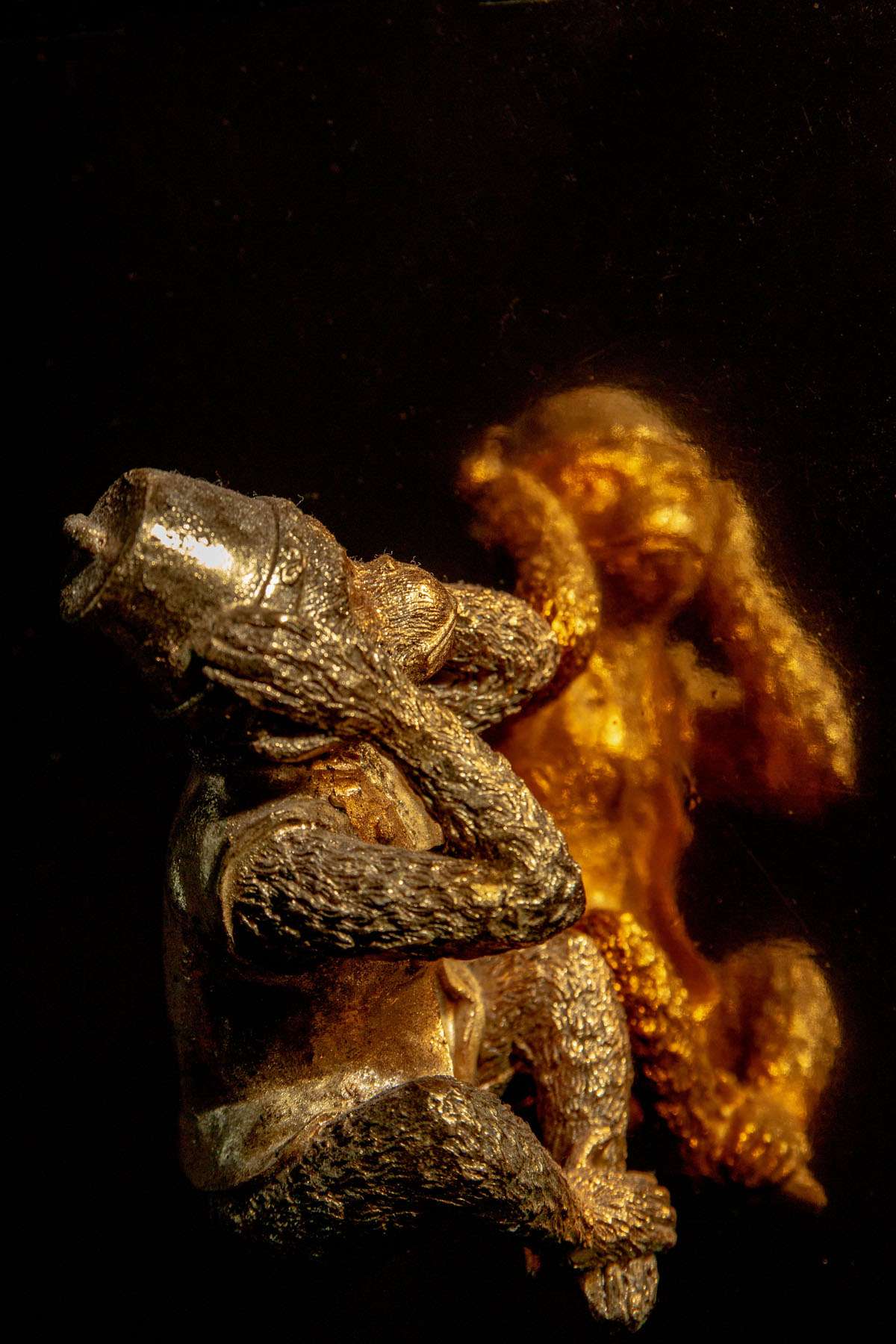 Photo of a brass monkey hear no evil reflected on golden card